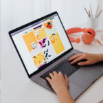 Hands typing on a laptop displaying a colorful digital media layout, illustrating creative web design and user experience strategy.